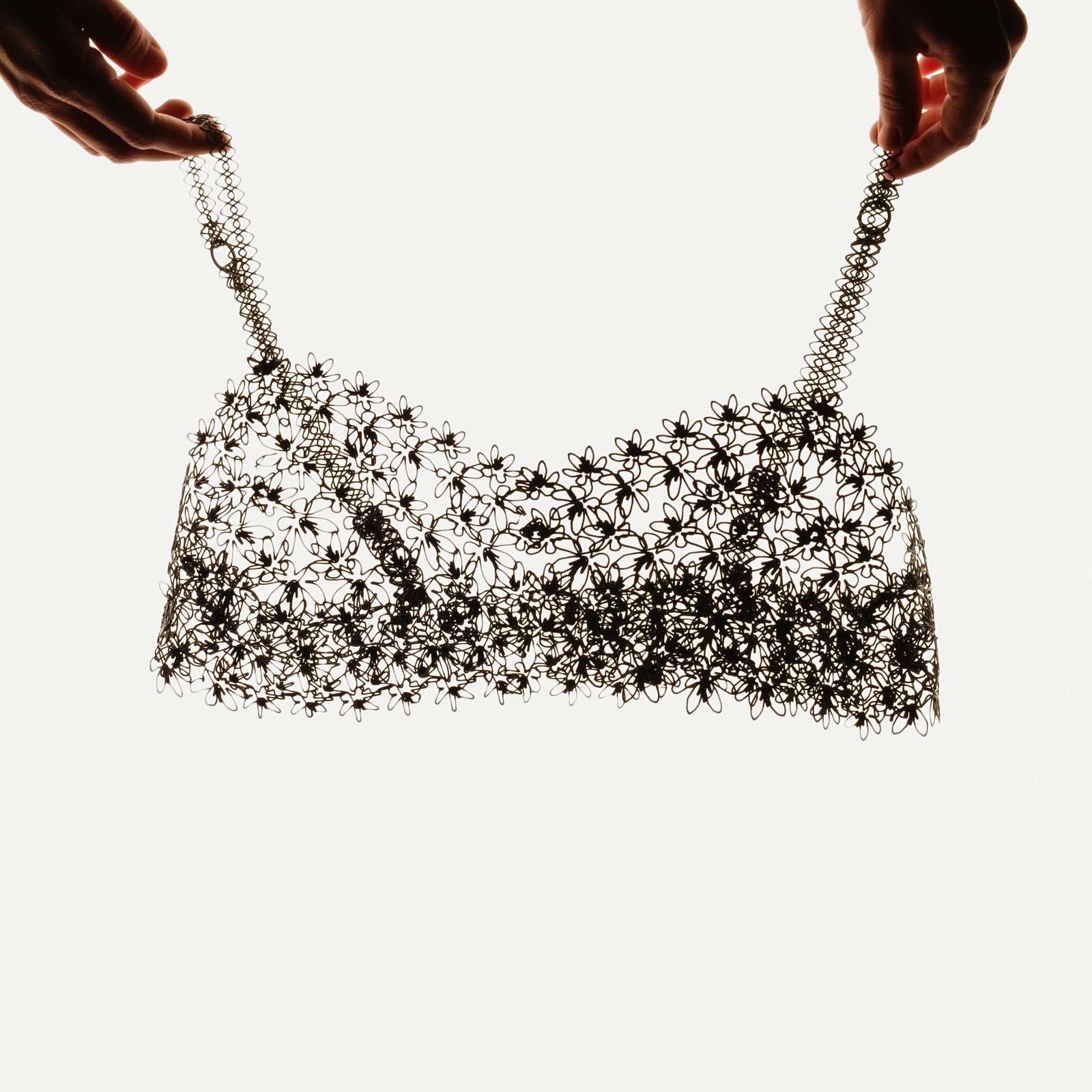 3D printed flower lace bra held up against the light
